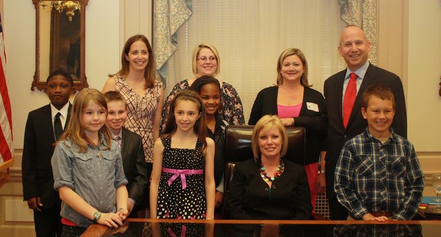 Governor Markell (standing right) and Senator Nicole Poore (seated, 2nd from right) meeting with students from Southern Elementary before the vote to make cycling the Officials State Sport of Delaware.